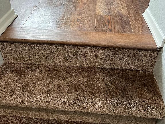 Detailed series of views showcasing the skill of the flooring installer in transitioning form carpet to vinyl at the top of the stairs.