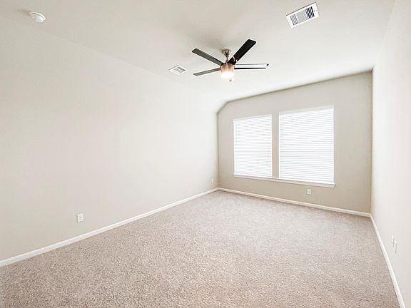 Another view of the home office/study with ceiling fan and large windows