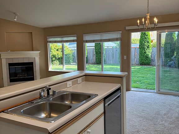 open concept kitchen, dining and living room with gas fireplace and sliding glass patio door that opens to the large fenced backyard
