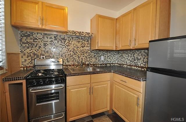 New kitchen with stainless steel appliances and decorative glass tile back splash.