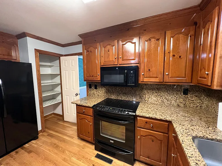 Photo of flat top electric range and microwave. Plenty of cabinet space and pantry closet