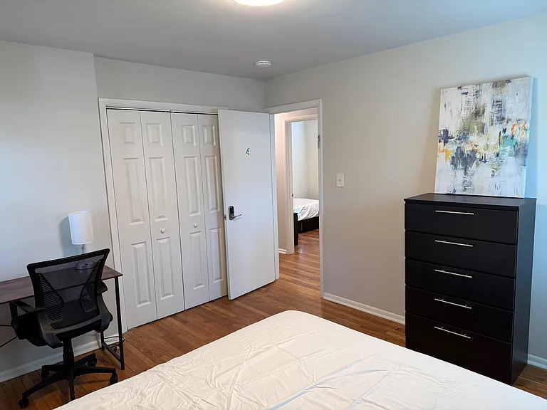Private bedroom with hardwood floors, a roomy closet, dresser storage, and a dedicated desk area for work or study.