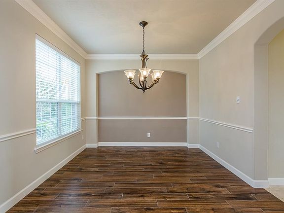 The formal dining room is spacious, has high ceilings, crown molding, chair rail and window with views of the front yard. Note the beautiful builder details including the large arched room opening and oversized niche that is perfect for furniture.