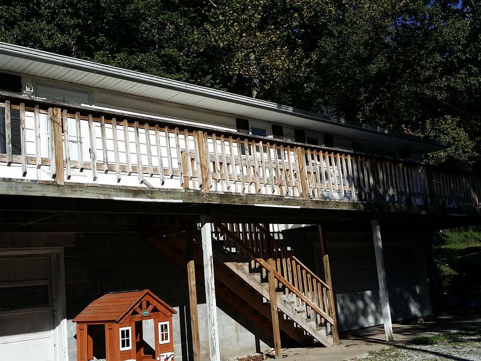 Large Front porch with stairs set against a hillside of tree