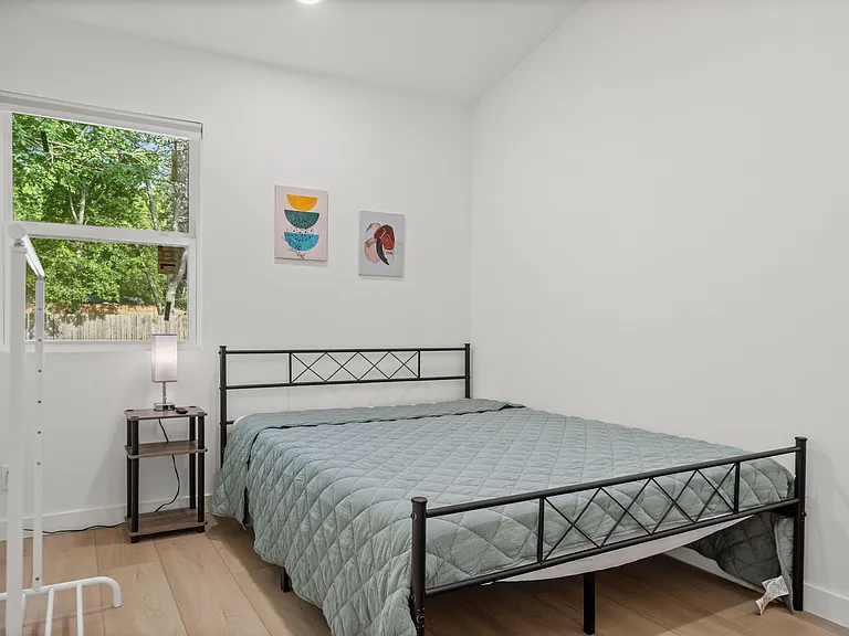 Private bedroom with a full bed, nightstand lighting, and a large window offering calming views and natural light.