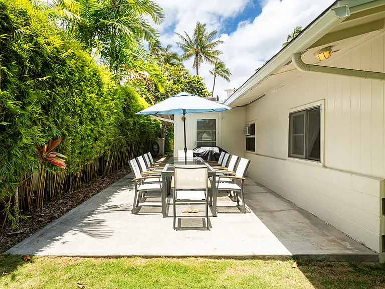Covered outdoor dining patio with space for entertaining, surrounded by mature bamboo and tropical landscaping.
