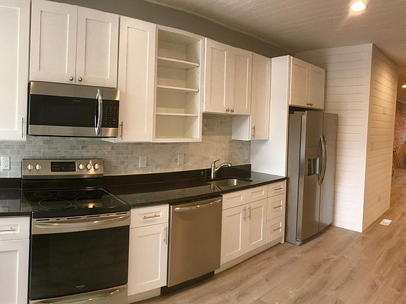 New kitchen with stainless steel appliances, granite counters and marble backsplash