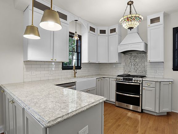 Kitchen features farmhouse sink and stainless appliances.