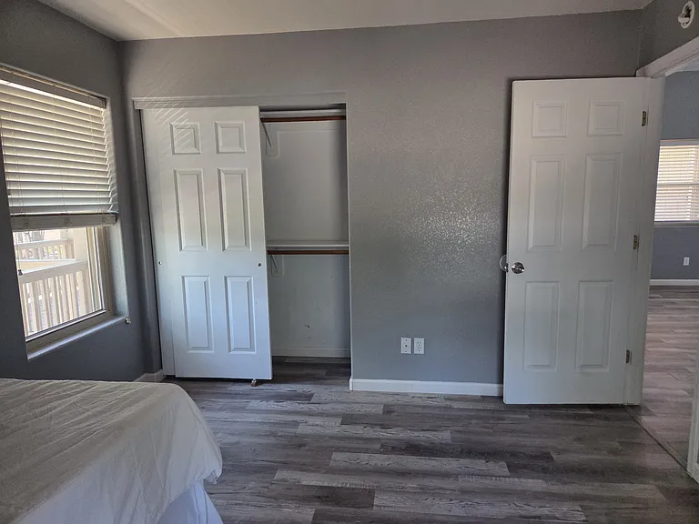 Second bedroom with two windows, located across a short hallway to the second bathroom. Closet features an upper and a lower shelf as well as two closet rods.