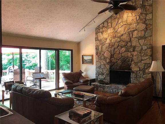 Family room with cathedral ceiling, gorgeous stone gas starter/wood burning fireplace & a wall of glass sliding doors for tons of natural light & access to deck & private wooded backyard!
