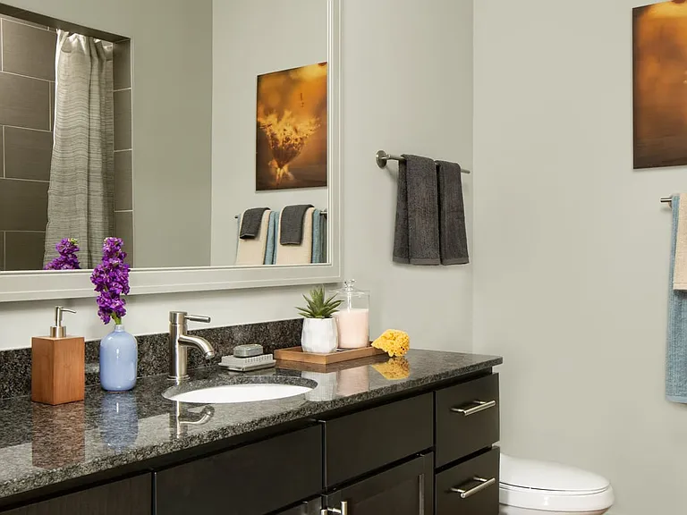 Apartment bathroom with glass enclosed shower and wood-style flooring.