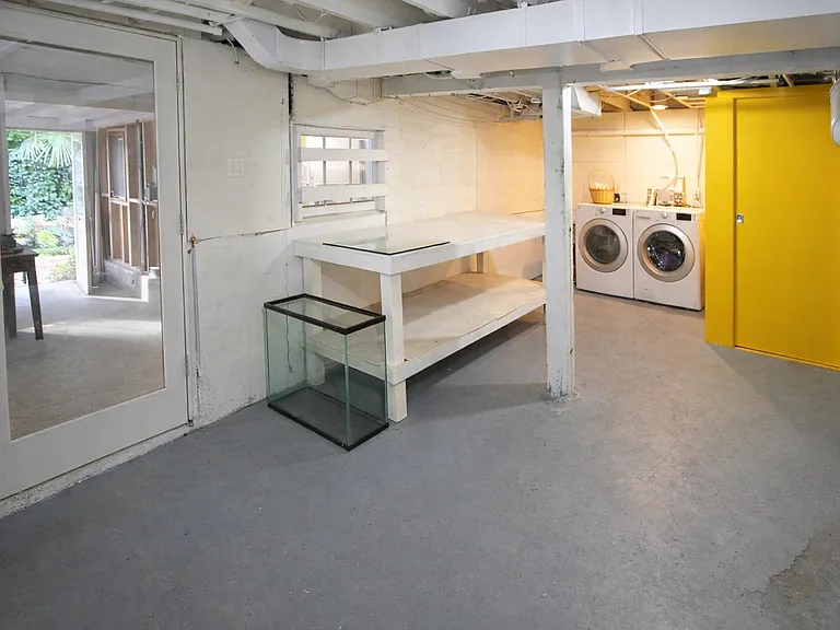 Laundry room in daylight basement next to full bathroom (tub and shower and utility sink) behind yellow door.