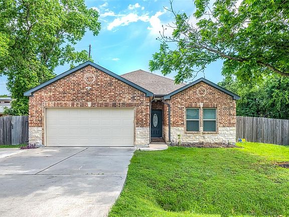 Front of the house with 3 car wide driveway. Landscape lighting at night