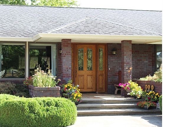 Covered entry offers a warm welcome to friends and family with brick columns and planters.