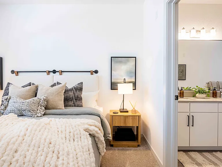 This primary bedroom in the Garrett Parker B1 floor plan connects directly to an en suite bathroom with a double sink vanity.