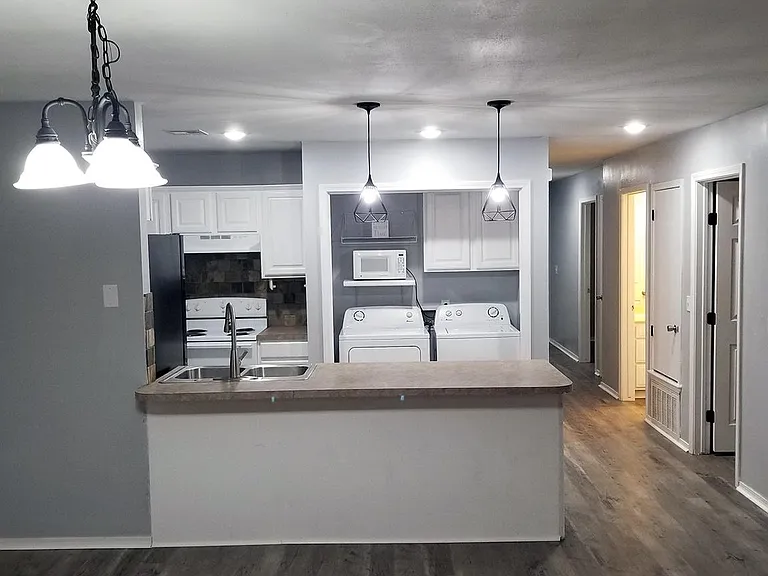 View to kitchen from living room (on the right, you can see the light on in the central bathroom, between the front (1) and center (2) bedrooms).