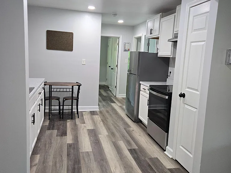Updated galley kitchen with white cabinets, stainless appliances, and a breakfast nook, plus durable plank flooring.