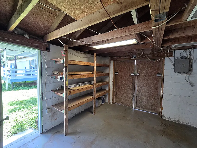 Storage area with ramp in back and door to shop with trailer in background