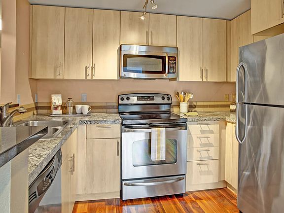 A kitchen with stainless steel appliances, stone countertaps, a small breakfast bar, and lots of cabinet space