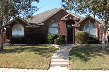 Nice landscaping with raised stone borders and large trees.