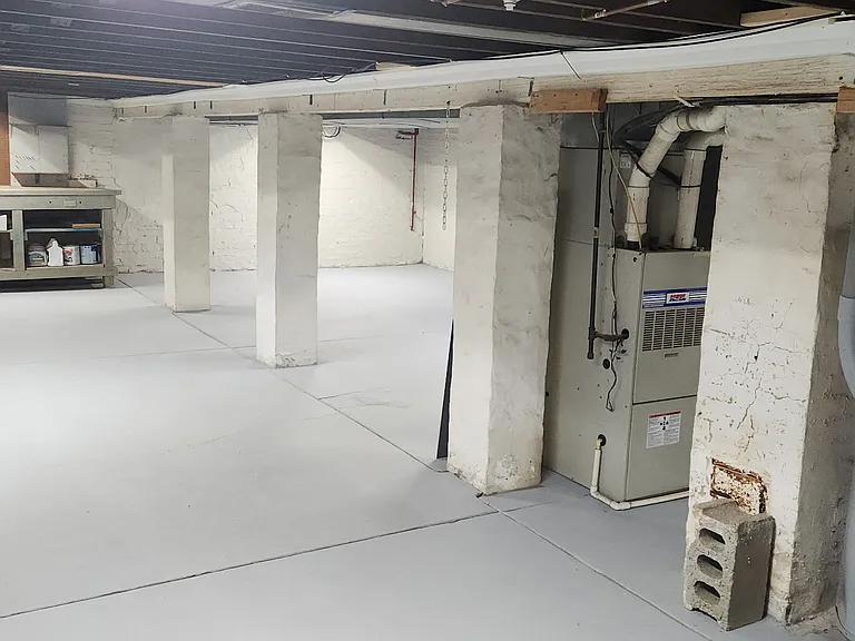 View of the spacious basement showing the furnace and built-in workbench.