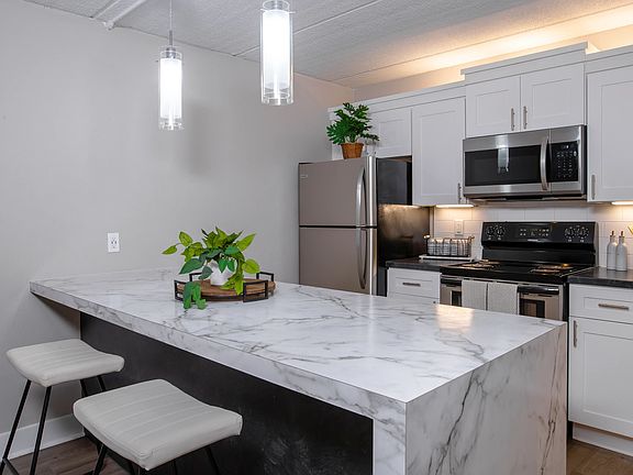 Our kitchens feature a spacious marble-style breakfast bar, stainless steel appliances, and elegant pendant lighting.