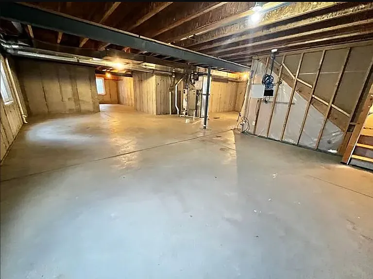 View of the large, unfinished-garage as viewed from the northwest corner. The stairs leading upstairs can be seen on the far right side of the photo. The garage is the same size as the lower level of the house.