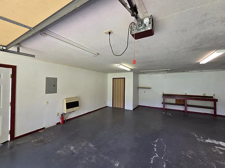 2 car garage with space heater and half bath as well as garage door openeer in background