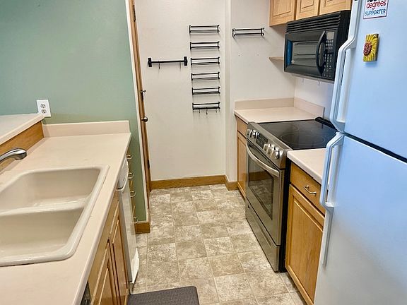 Galley kitchen with newer appliances and pantry closet for storage.