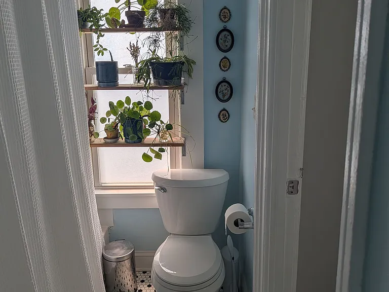 From the sink in the bathroom. Back bedroom to the right. Bathroom with tile floor, bathtub, shower and plant shelves.