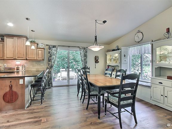 View of dining and kitchen from great room. Dining is open to kitchen for easy entertaining, and features a fun window seat and lovely twin built-in lighted china cabinets. Patio doors straight ahead lead to one of your two decks. >