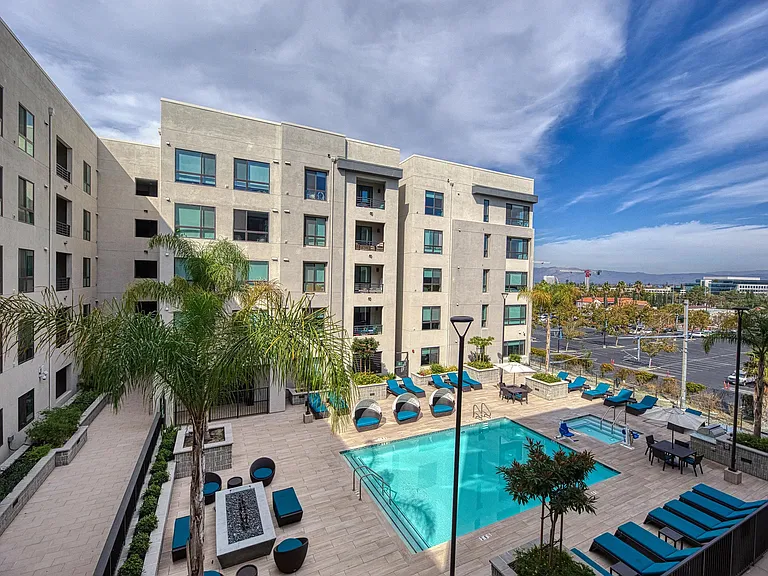 Expansive pool terrace with seating, palm trees, and a firetable that enhances the outdoor experience.