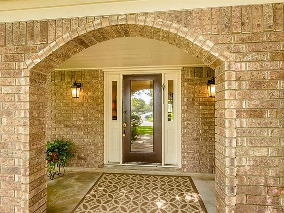 The arched opening to the large front porch leads you to the pretty glass front door that invites you in to this lovely home.