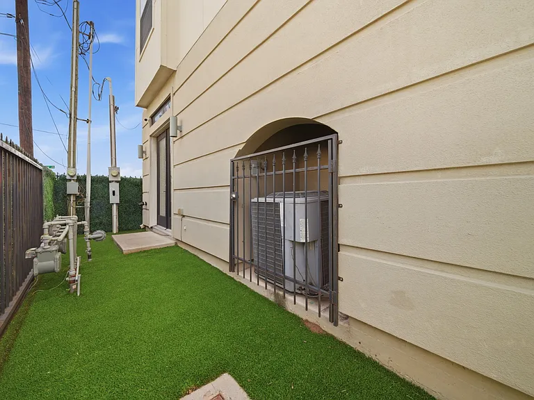 Utility area located along the side of the home featuring low-maintenance artificial turf, HVAC system, and utility meters.