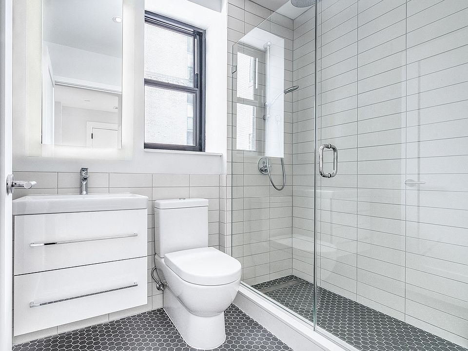 Bright tiled bathrooms with large backlit designer mirror, Hans Grohe chrome fixtures and Villeroy & Boch vanity