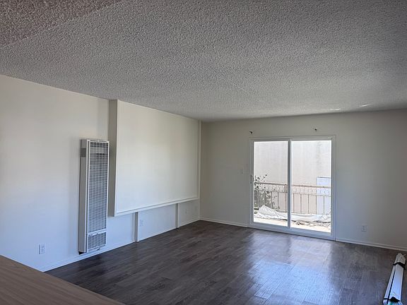 Living room with new furnace, new sliding glass door, mid-century-modern wood wallpaper panel (blinds on floor and materials on balcony have since been removed from floor and installed)