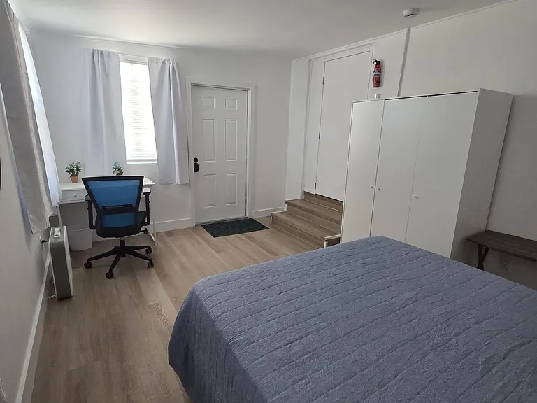 Well-laid-out bedroom with a work desk, wide closet storage, and wood-look flooring near a private entry.