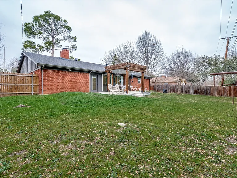 Expansive backyard featuring a lush lawn, privacy fencing, and a red brick exterior
