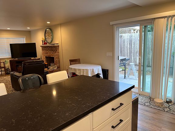 Kitchen open to dining and living room with access to private patio and deck.