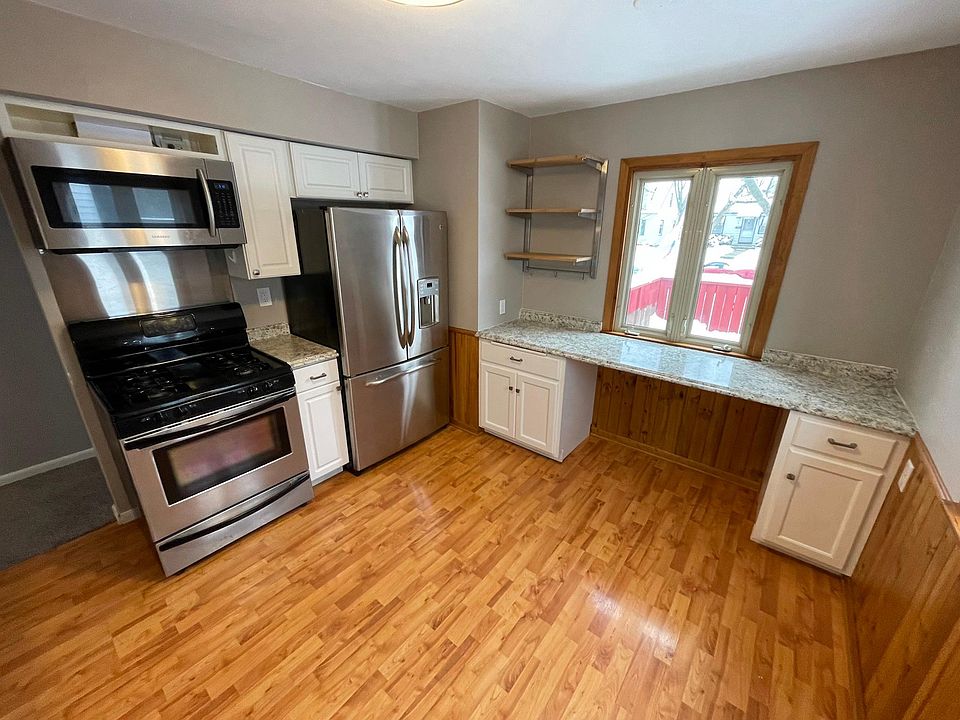 Newer SS appliances with breakfast counter and additional open shelving.