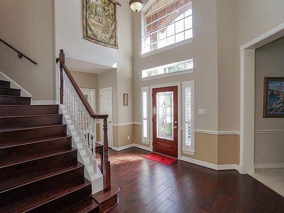 Entry features leaded glass door with side panels, plantation shutters & gorgeous hardwood flooring.