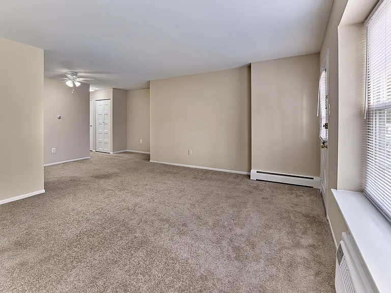 Spacious living area with wall-to-wall carpet and abundant natural light at 42 West Apartments