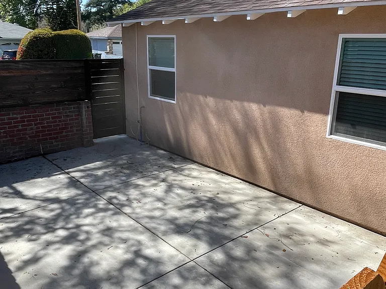 Private, gated cement patio area with space for outdoor seating and added privacy; entrance to backyard.