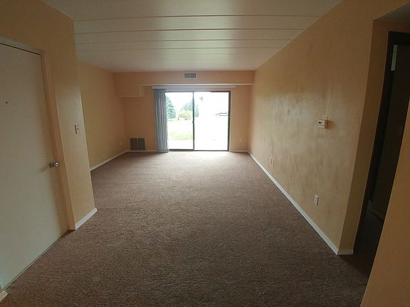 Entrance to apartment and living room with access to patio overlooking large green space