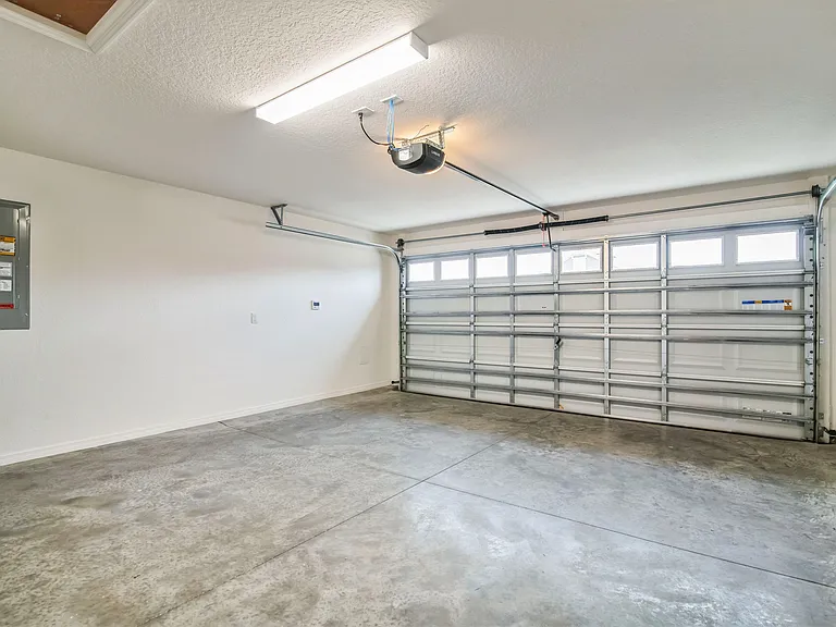 Spacious Two Car Garage with a Single, Quiet Garage Door and Access to Electrical Panel and Tankless Heater Thermostat and Valve.