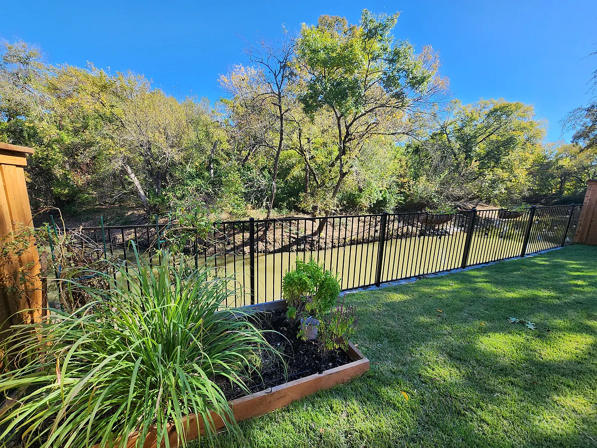 View of creek and forest; raised garden bed and baskets on fence are watered by automated sprinkler system - 929 Parker Dr