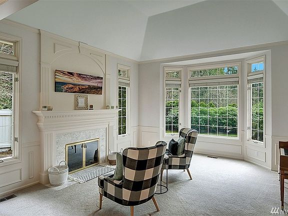 The formal living room features a tall coved ceiling with crown molding, wainscoting and marble surround gas fireplace. 