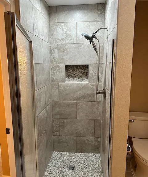 Newly refurbished shower features all new tile surround and floor, new fixture and glass door.
