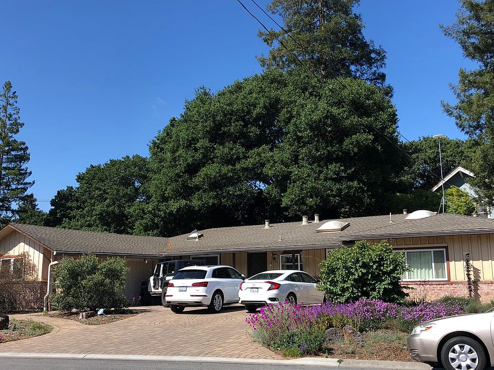 Front of house facing street. 2-car garage on left. Low-maintenance yards with many California natives. Tall redwoods & oak behind house