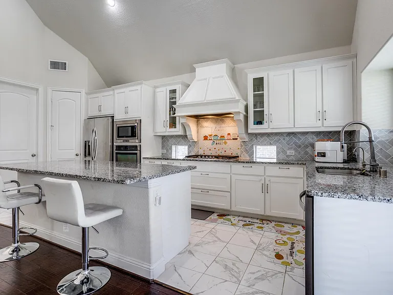 Kitchen featuring light hardwood / wood-style flooring, custom range hood, stainless steel appliances, vaulted ceiling, and a kitchen island